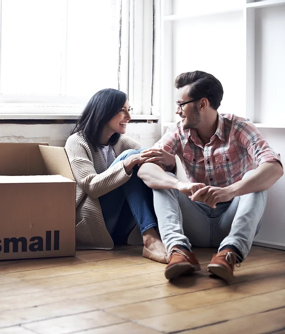 A couple sitting among moving boxes in their new home