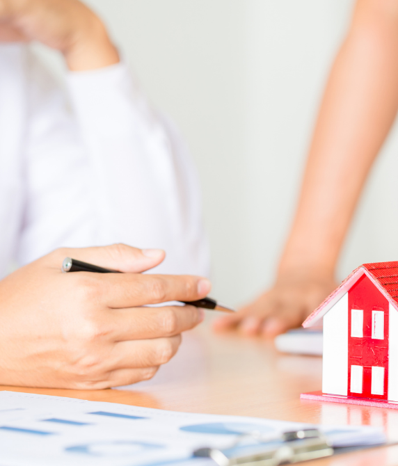 A medical professional reviewing documents beside a model house